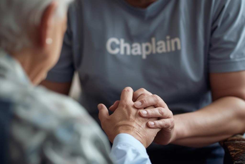 Hospice chaplain holding patient’s hands in prayer and comfort, providing spiritual care during end-of-life support